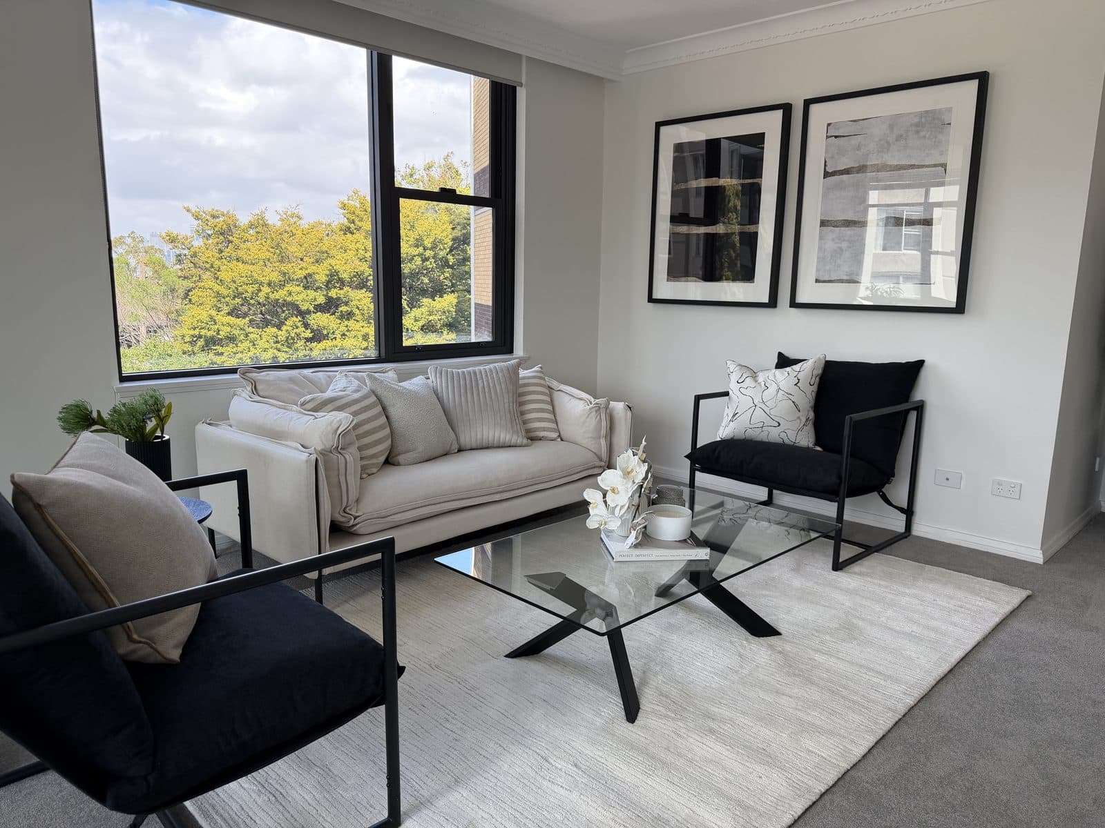 Apartment living room styled with black armchairs, cream sofa and monochrome artwork — apartment styling Sydney