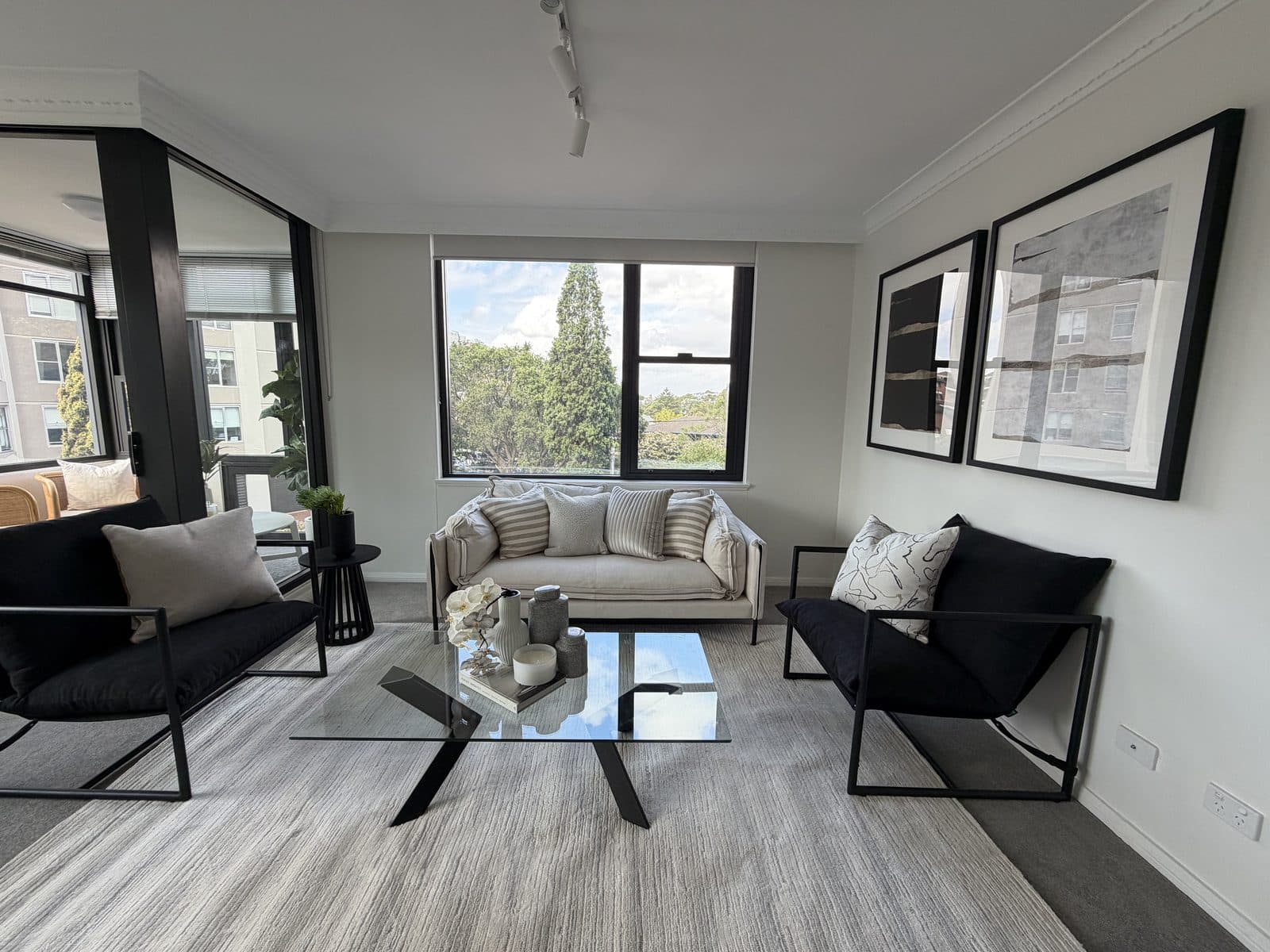Open-plan apartment living room with glass coffee table and black framed artwork — apartment styling Sydney