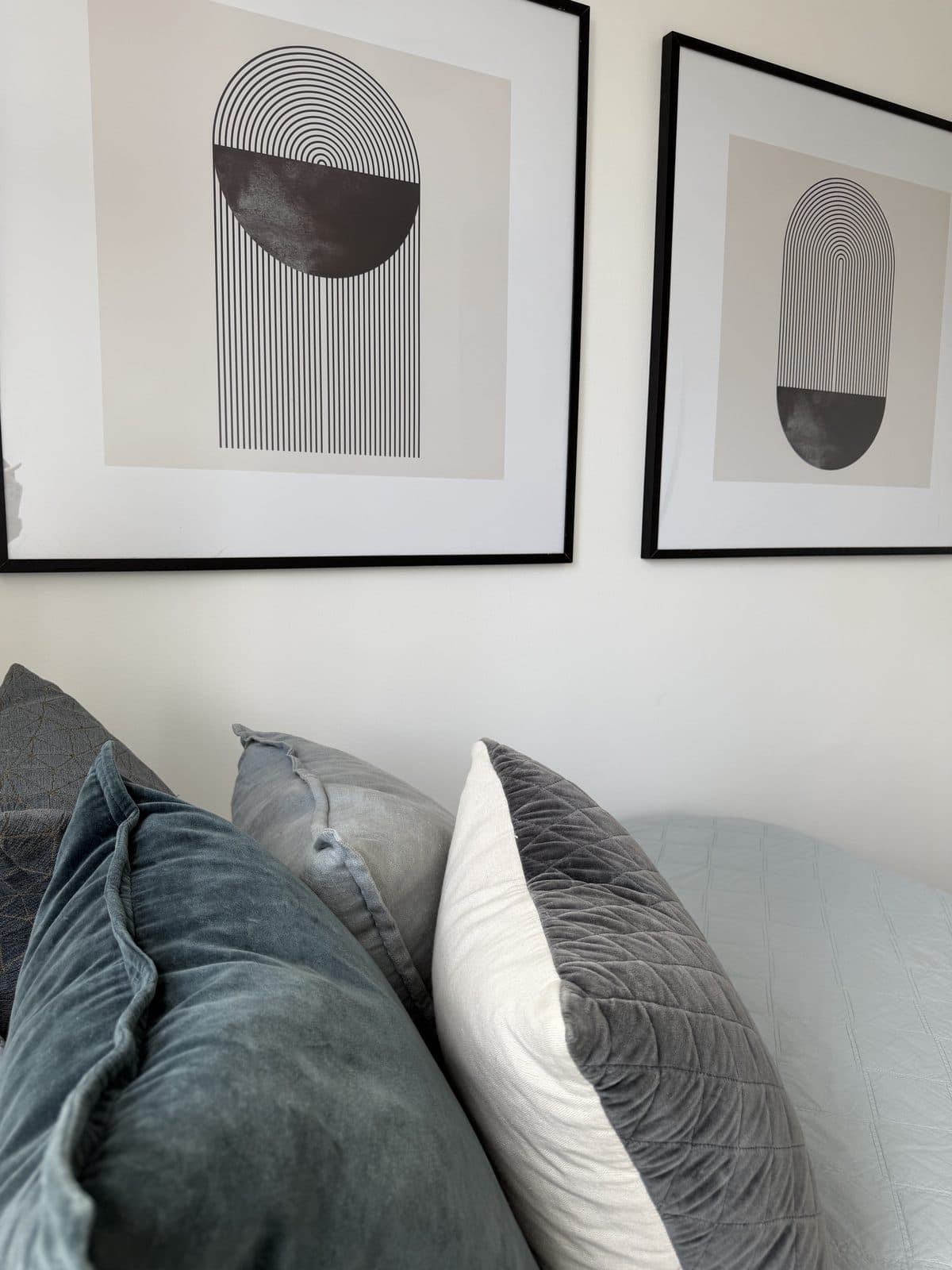 Bedroom styled with monochrome arch artworks and blue velvet cushions — apartment styling Sydney