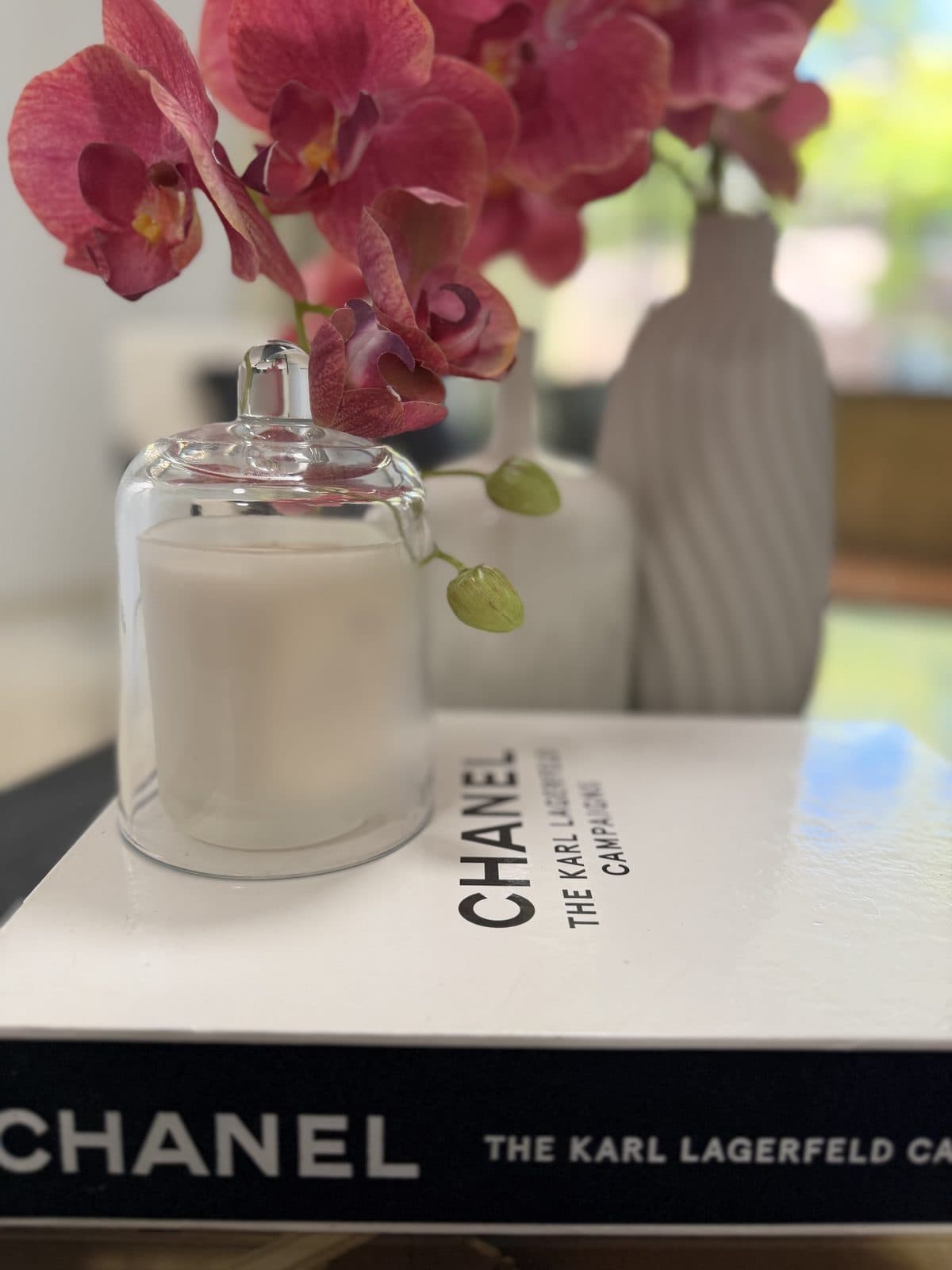 Coffee table vignette with pink orchid, candle cloche and coffee table book — apartment styling Sydney