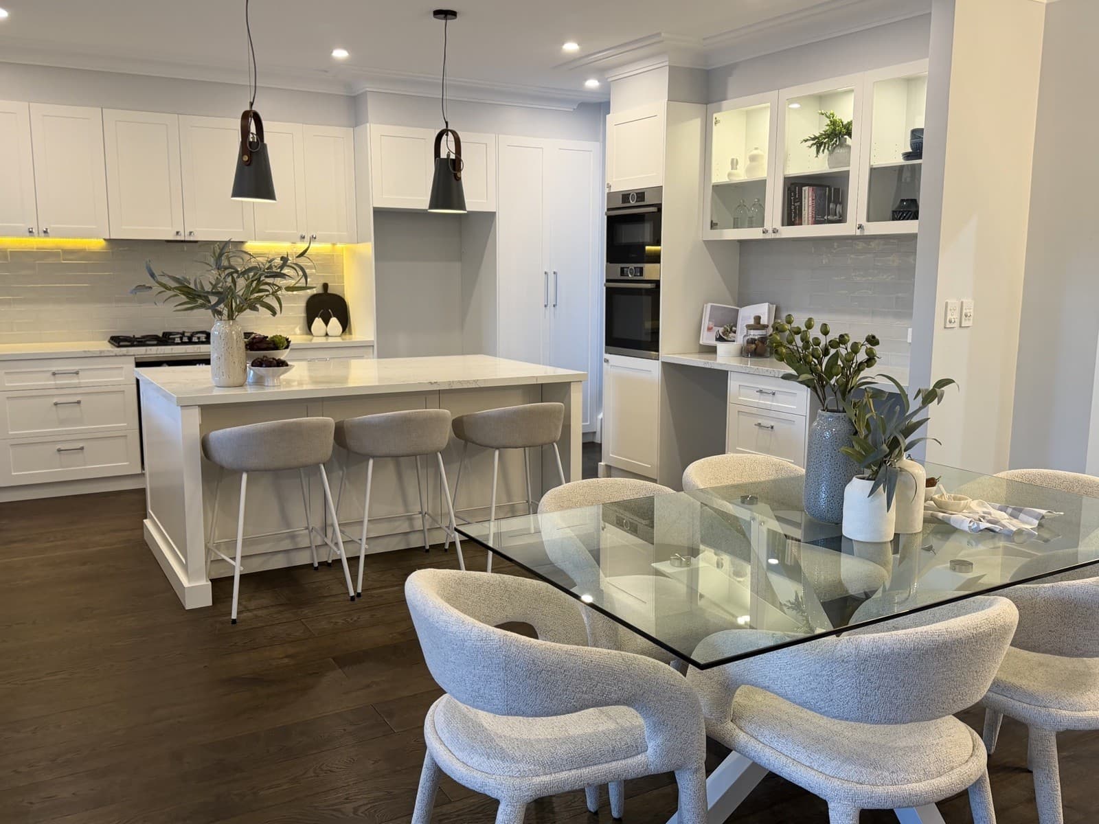 Open-plan kitchen and dining area styled with glass table — property styling North Shore Sydney